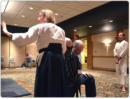 Milwaukee County Circuit Court Judge Mel Flanagan demonstrates a hold on Reserve Judge Timothy L. Vocke during the Personal Security for Judges presentation at the Judicial Conference.
