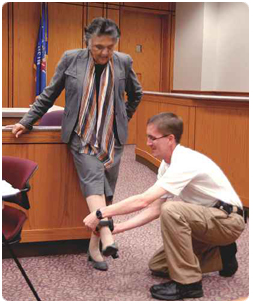 During a demonstration of an inmate work-release program, Aaron Ellis, a supervisor at the Dodge County Detention Facility, placed an ankle monitoring bracelet on Chief Justice Shirley S. Abrahamson. Abrahamson was in Dodge County to announce a new outreach initiative. During the visit, local officials took advantage of the time to share information about their own programs. Photo credit: Watertown Daily Times