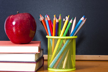colored pencils next to a stack of books and an apple